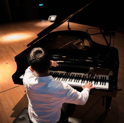 back-view-photo-of-a-man-playing-a-black-grand-piano
