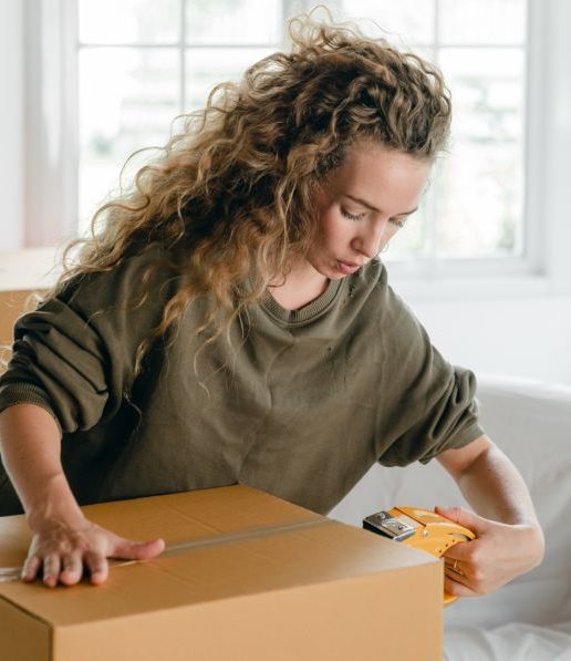 focused-young-woman-packing-carton-boxes-with-adhesive-tape